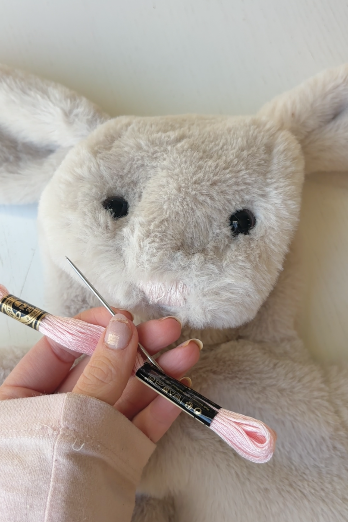 Stuffed animal in a red dress sitting on a white surface with a blurred indoor background. Plushie plush bunny sewing pattern tutorial, making build-a-bear, diy plushie, diy bunny, making toy toys, build-a-bear clothes, homemade Christmas gift, tiktok sewing pattern, homemade toy, homemade plushie, plushie pattern, bunny pattern, birthday gift child,